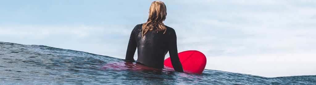 An image of a surfer sitting on a surf board waiting on a wave in the ocean.