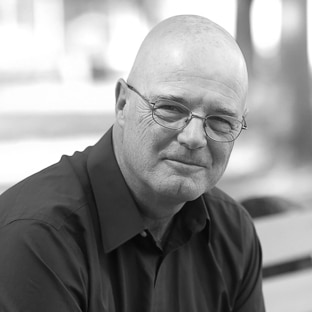 A black and white image of Brian McLaren in a dark shirt smirking at the camera.