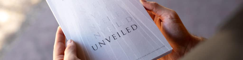 A person holding a copy of Oneing Unveiled