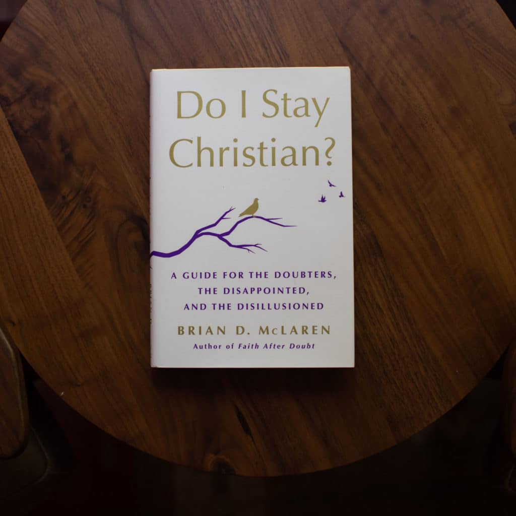 Do I Stay Christian? by Brian McLaren placed on top of a wood table.