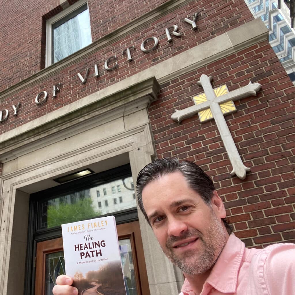 John S. standing in front of a church holding the book.