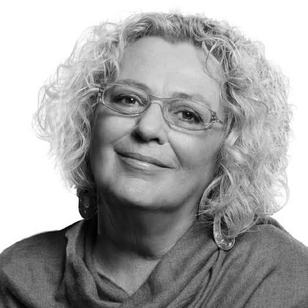Black and white photo of Kathleen Dowling Singh wearing glasses and a dark grey shirt and smiling