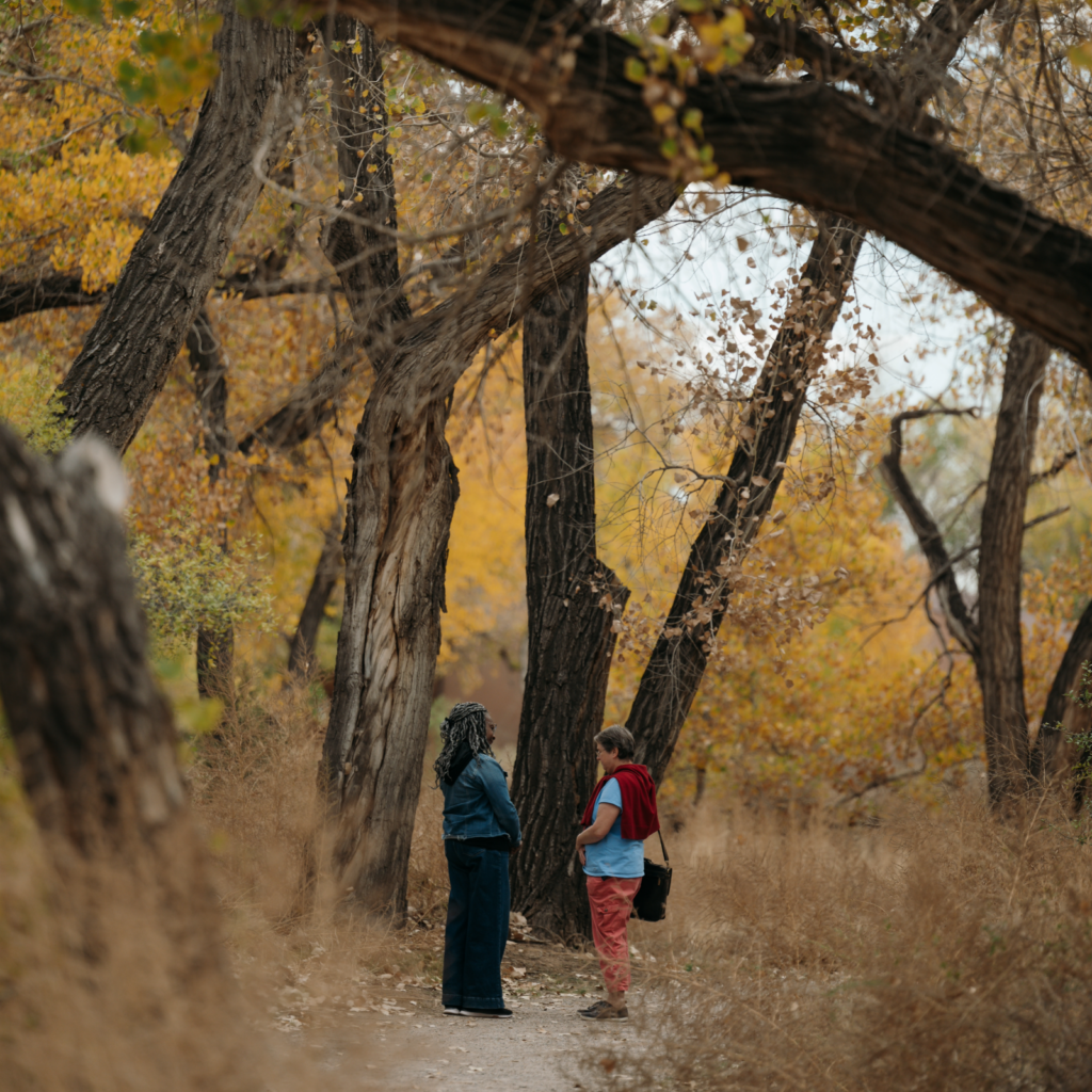 Two students converse under a tree at a CAC event.