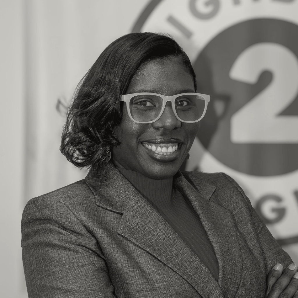 Professional woman smiling confidently in a gray blazer, showcasing leadership and empowerment in a corporate setting.