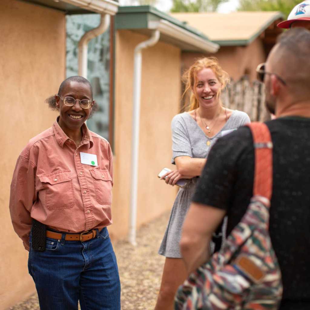 A group of CAC staff members engaging in conversation outdoors, showcasing smiles and a relaxed atmosphere in a casual setting.
